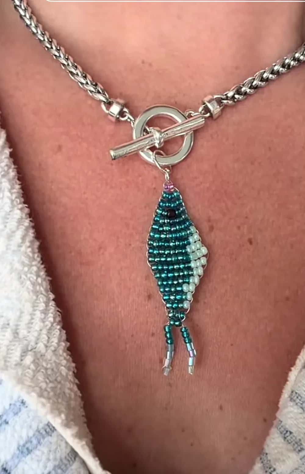 A teal and mint beaded fish pendant on a silver toggle-clasp chain