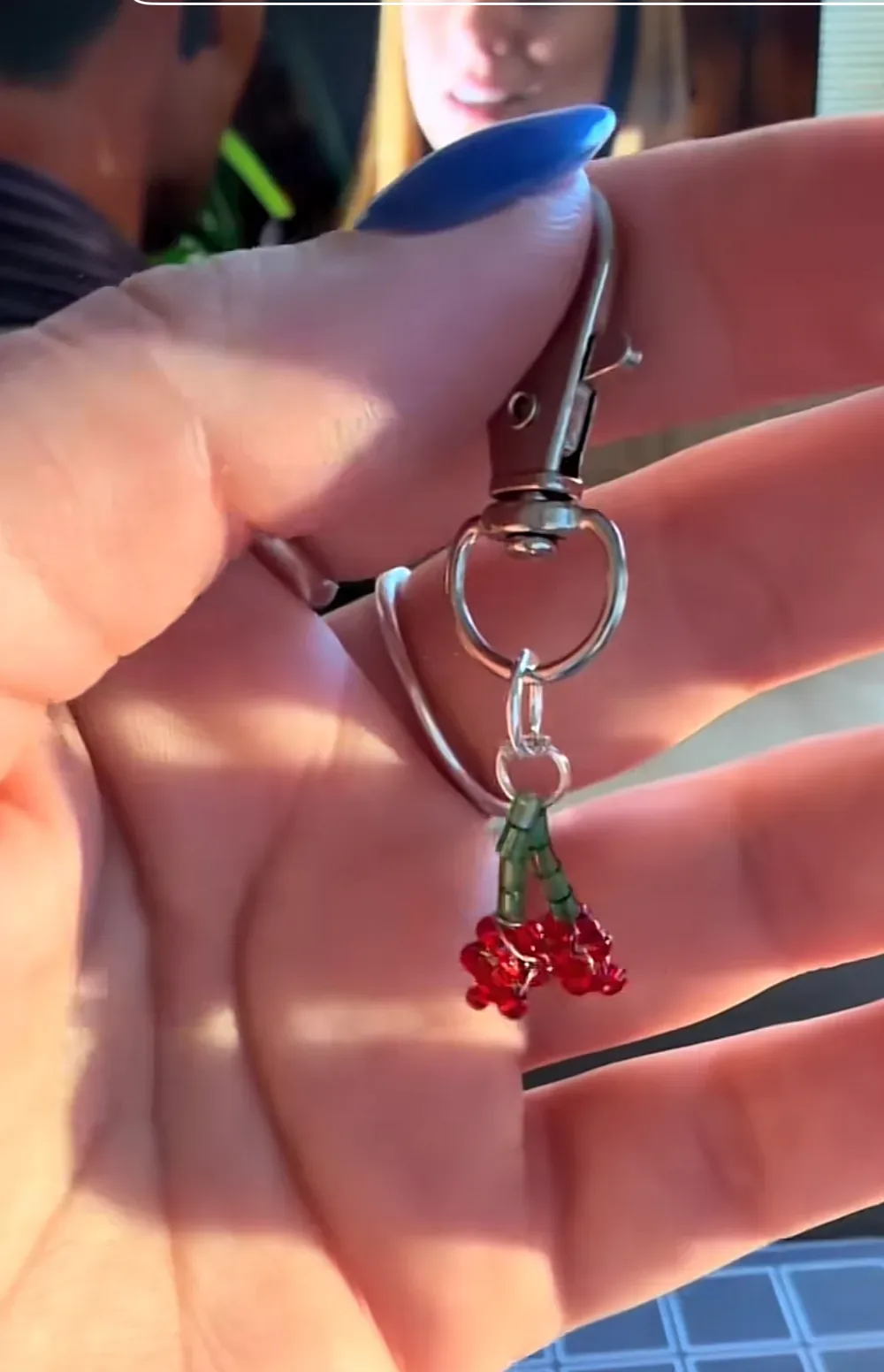 A small red beaded lobster charm on a silver keyring, held in a hand