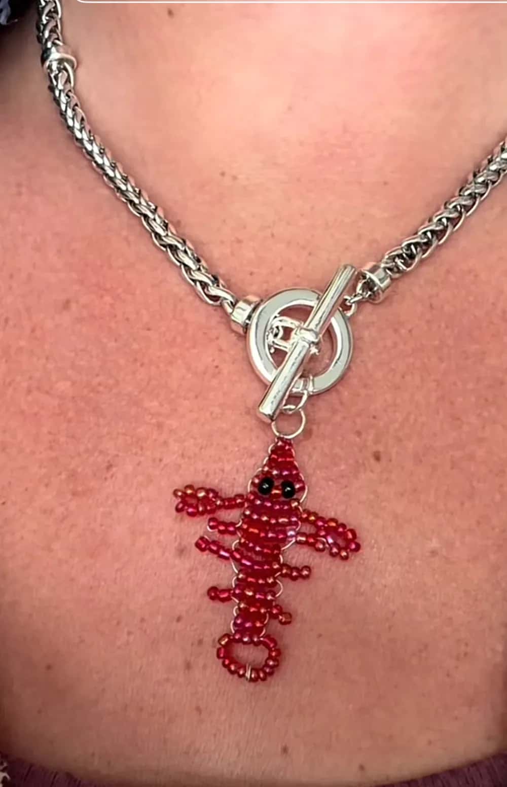 A red beaded lobster pendant hanging from a silver toggle-clasp chain